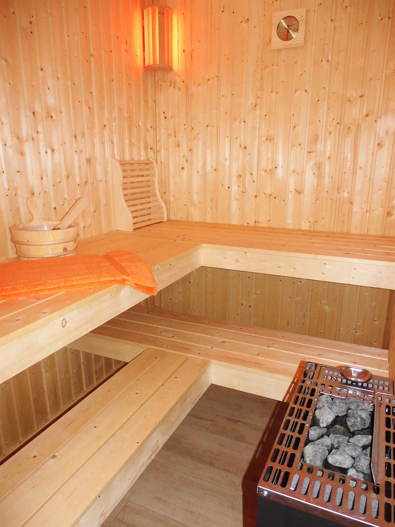 Sauna aus hellem Holz mit zwei Liegebänken und Saunaofen in der Ferienwohnung Auszeit in Baabe
